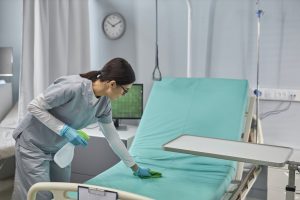 Nurse cleaning bed with sanitizer in ward